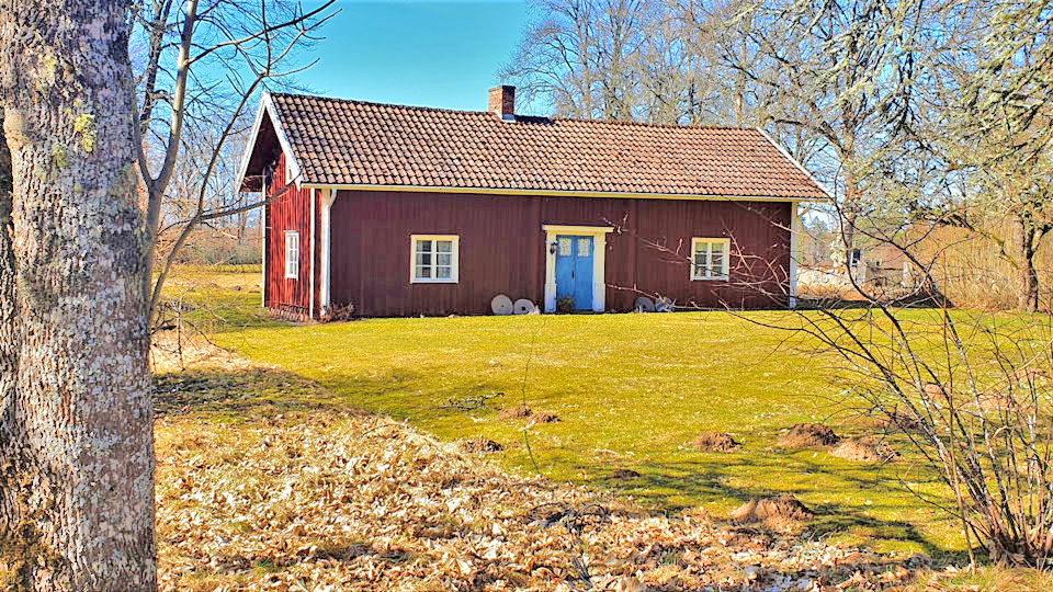 Hembygdsgård rött trähus med blå dörr och vita knutar