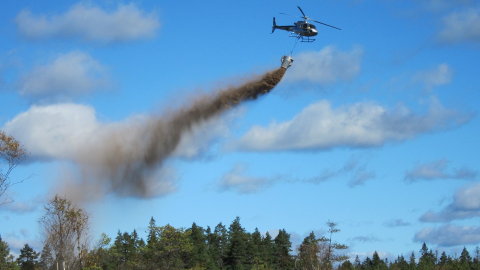 Helikopter flyger över sjö och skog 