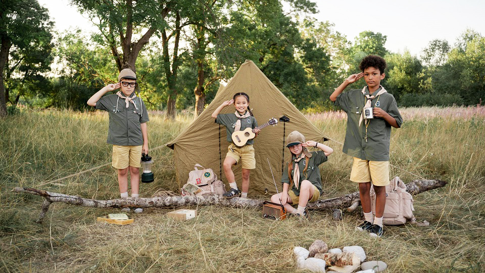 Fyra barn framför ett tält och en eldstad