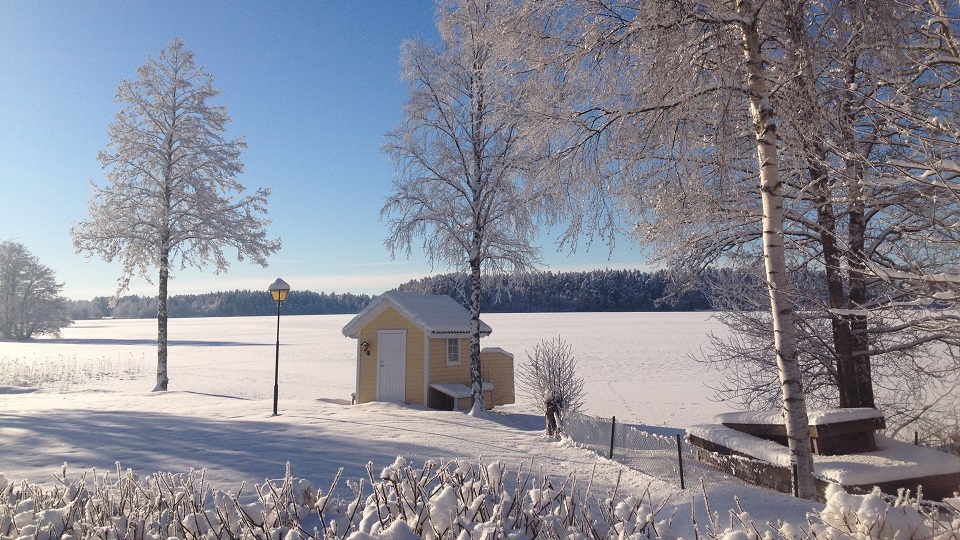 Solig vinterdag vid Mullsjön med klarblå himmel och tjockt snötäcke över isen.