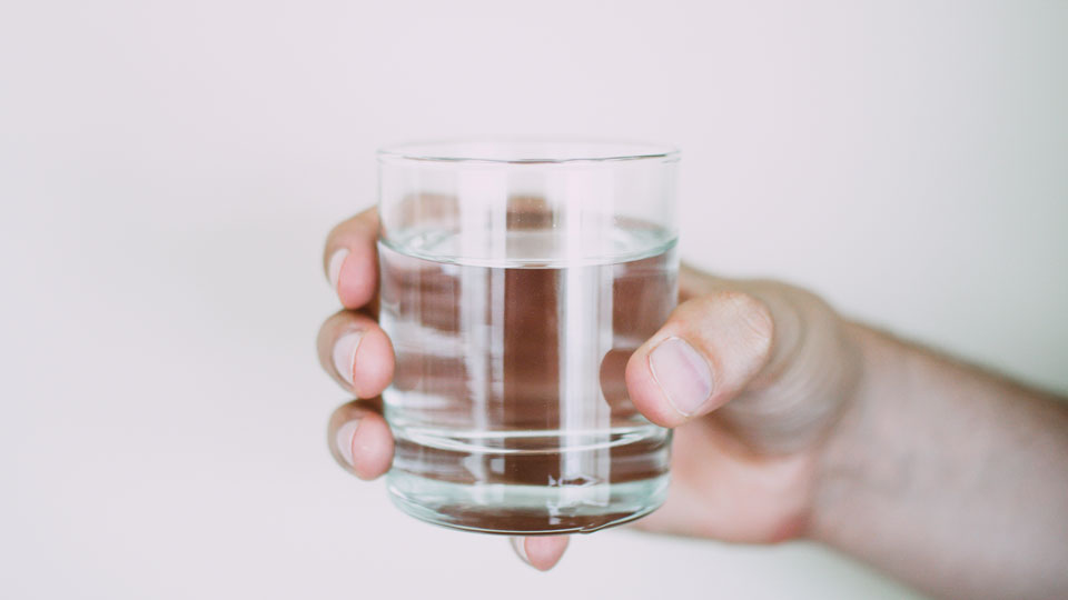 Hand håller glas med vatten