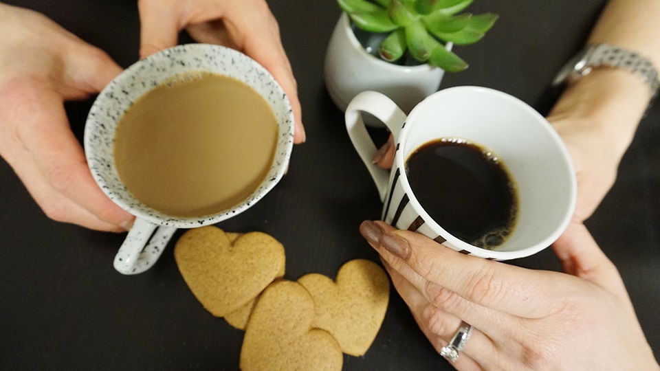 Två par händer håller i varsin kaffemugg.