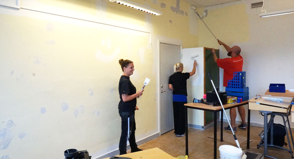 Tre personer målar om en vägg