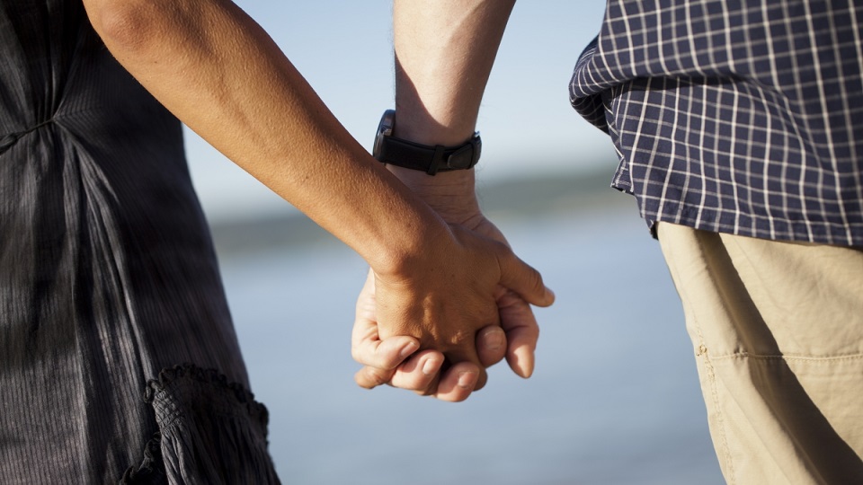 Bild på två personer som håller varandra i handen.
