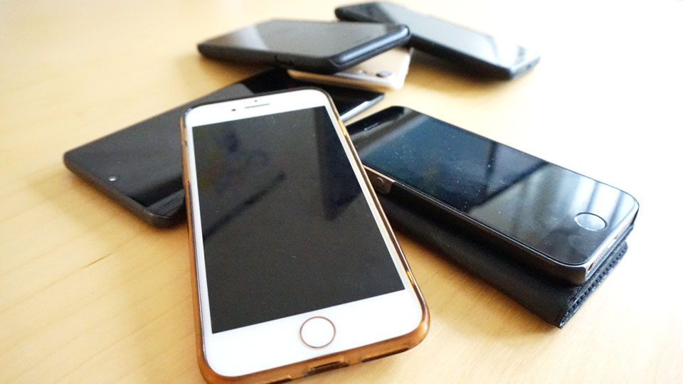 Bild på flera mobiltelefoner på ett bord.