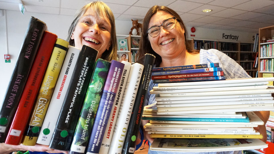 Bibliotikarierna Ingrid Halje och Ulrika Lundkvist håller fram böcker till försäljning