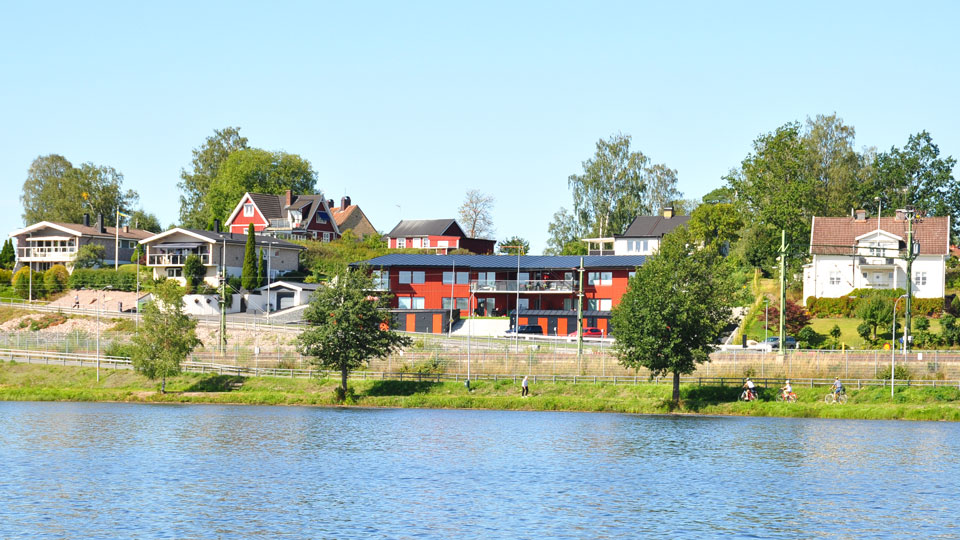 Bild på soldränkt hyreshus, Järnvägsgatan 7, från sjösidan