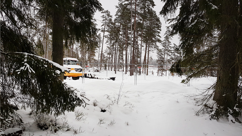 Dumper parkerad i snölandskap med träd runt omkring