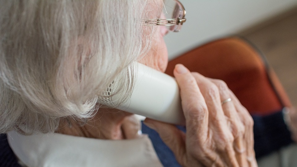 Äldre kvinna som håller en bärbar telefon mot örat.