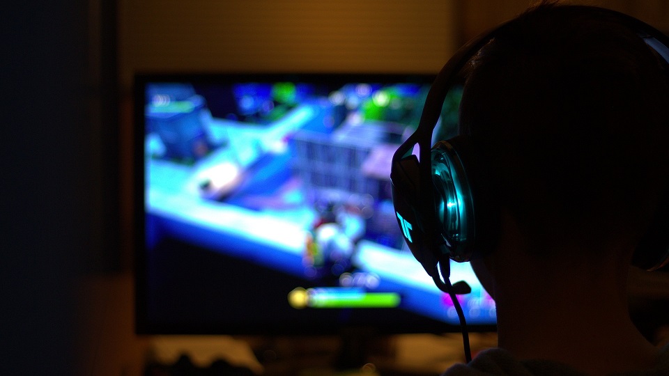 En person med gaming-headset som spelar dator.