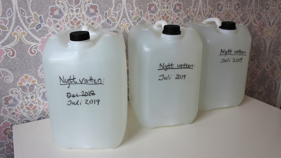 Bild på tre fyllda vattendunkar som märkts med det datum som vattnet fylldes på dunkarna.
