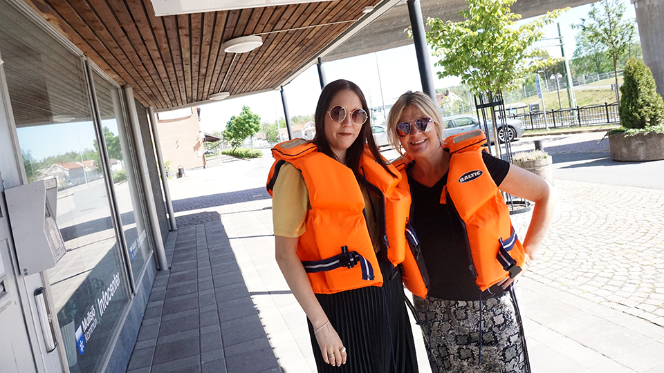 Två leende kvinnor står utanför Mullsjö kommunhus med varsin flytväst på