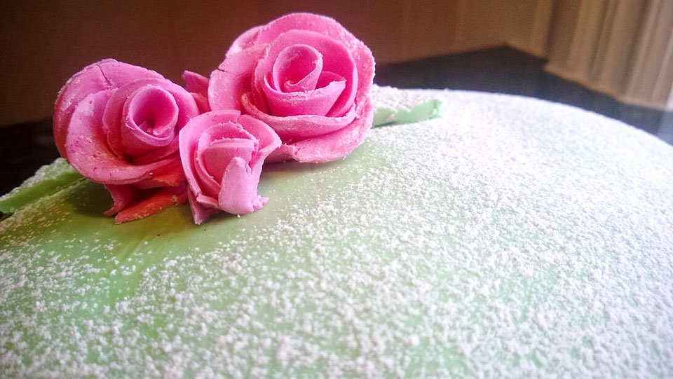 Närbild på grön tårta med rosa marsipanrosor