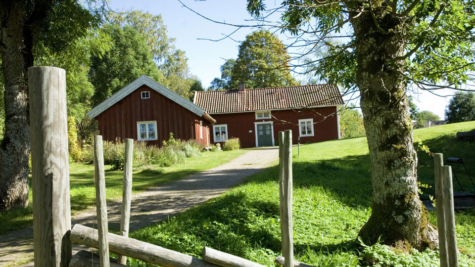 Rött hus med vita knutar bakom gärdsgård