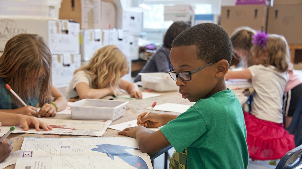 Barn skriver och ritar tillsammans i ett klassrum