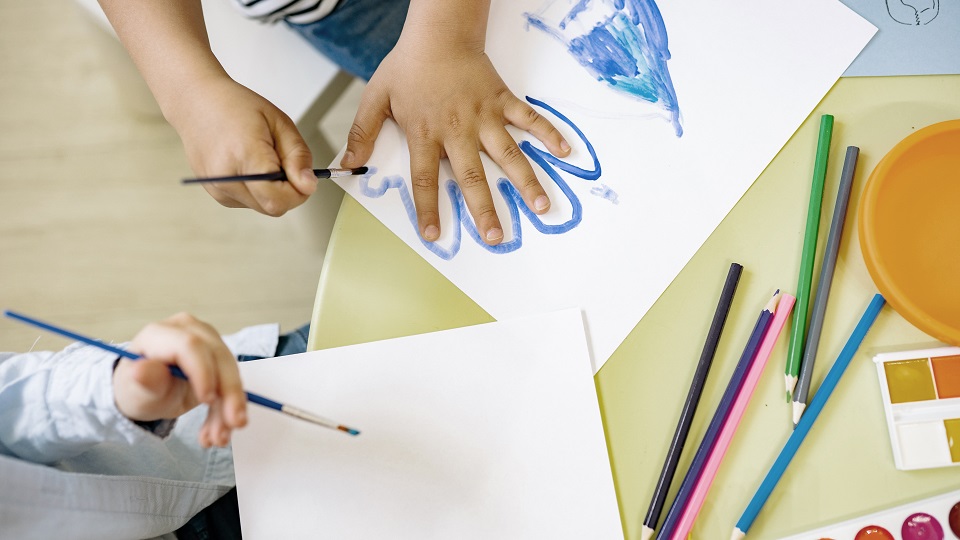 Barnhand som målas med streck runt om på papper