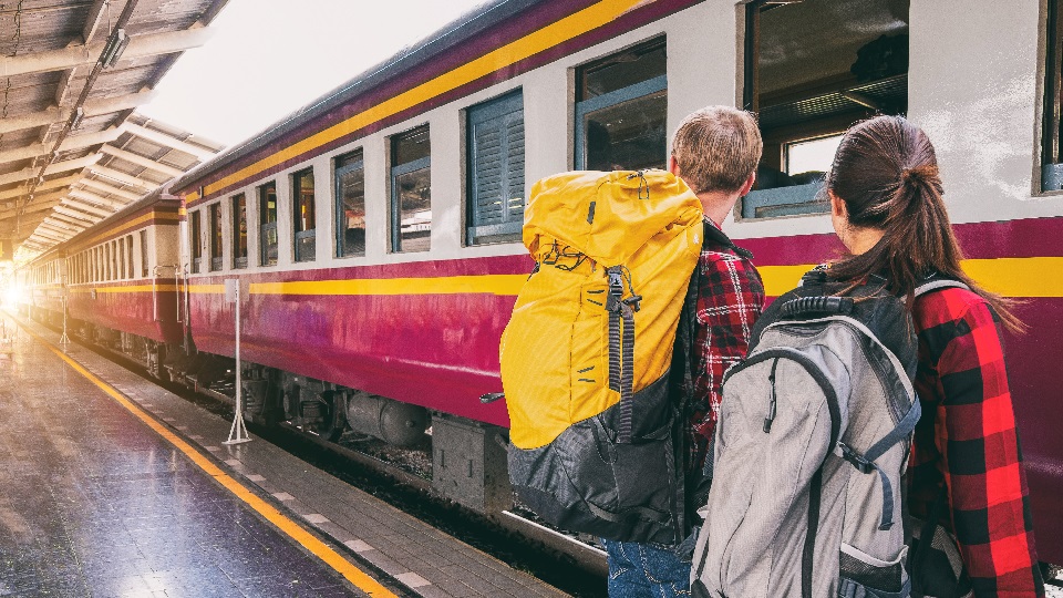 Två personer med ryggsäckar ska precis kliva på ett tåg