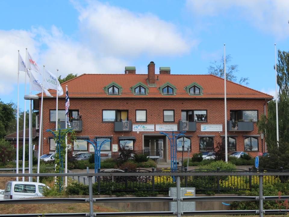 Bild på MEMABs kontor, ett tvåvåningshus i rött tegel med skyltarna "Mullsjö bostäder AB" och "Mullsjö energi och miljö AB"