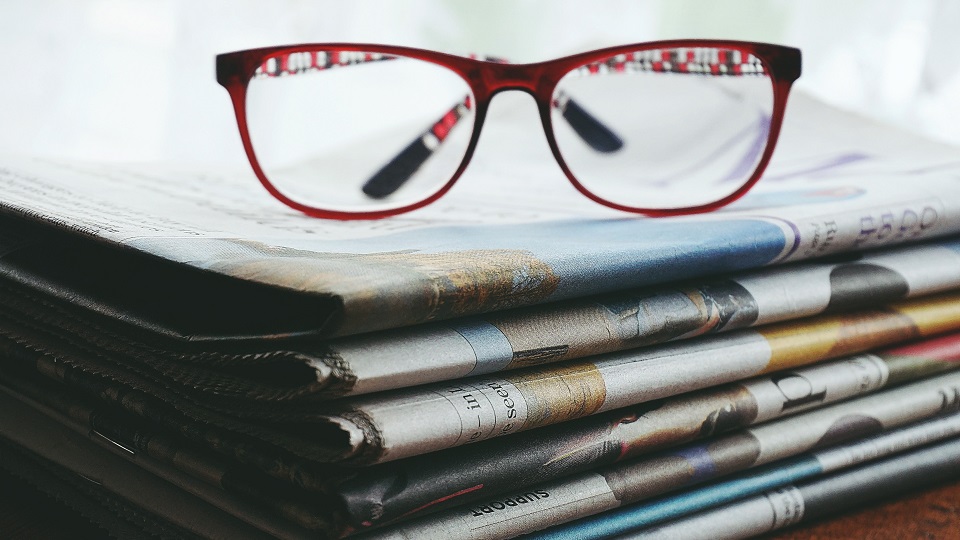 Ett par glasögon på en hög med tidningar 