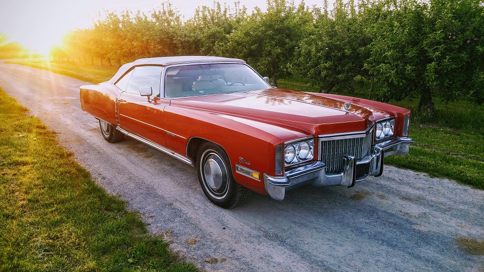 Röd Cadillac som står på en grusväg ute i naturen.