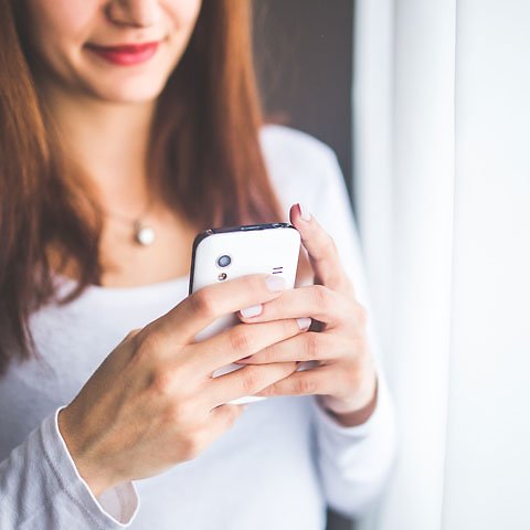 Kvinna står och textar på sin mobil