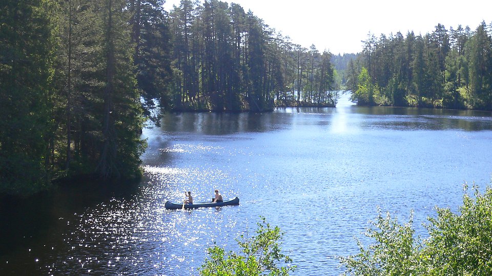 En kanot glider fram på en glittrande sjö