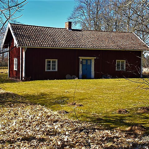 Rött hus med vita knutar och blå dörr